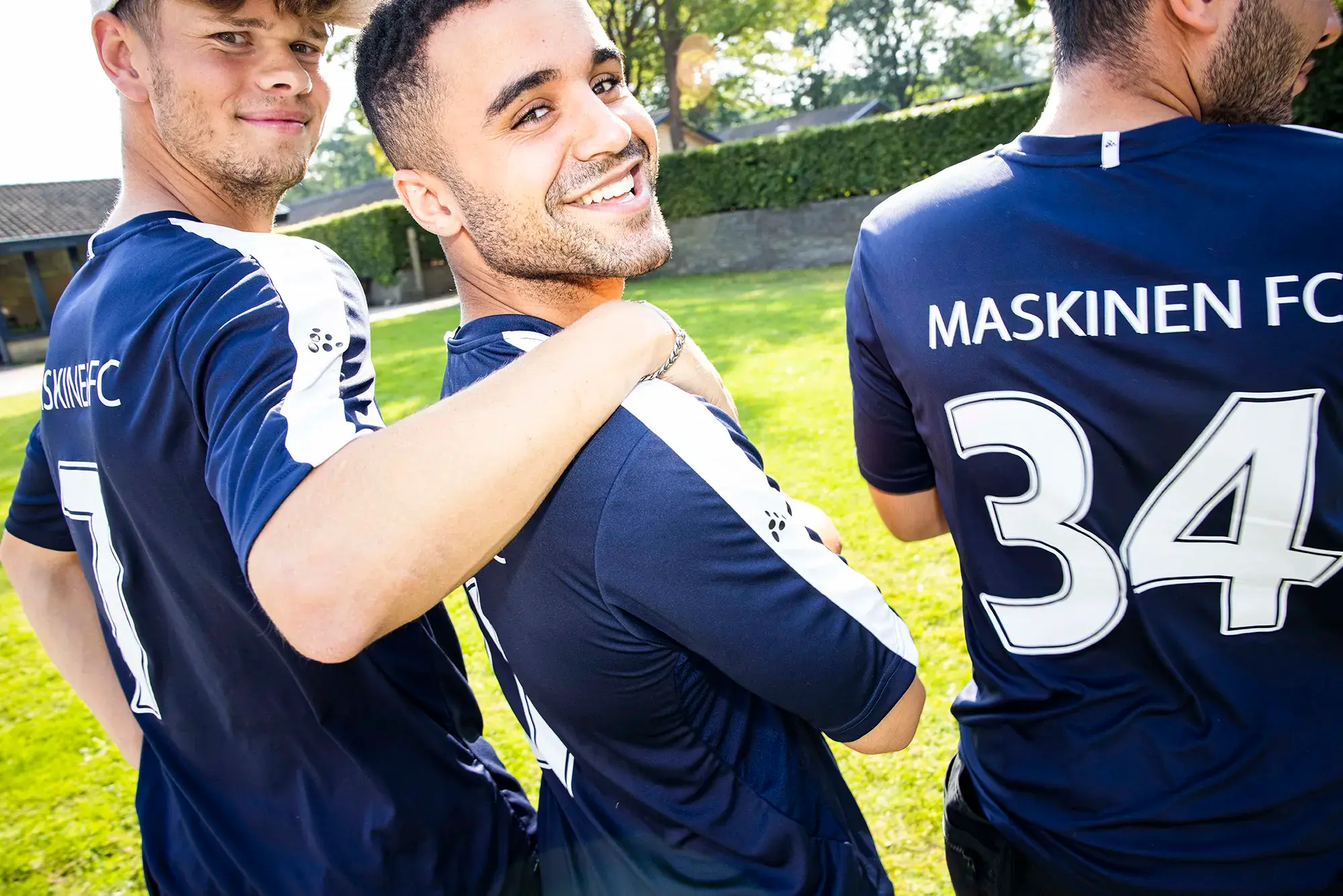 Tre glade studerende i Maskinen-fodboldtrøjer